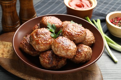 Photo of Delicious patties and spices on black textured table, closeup