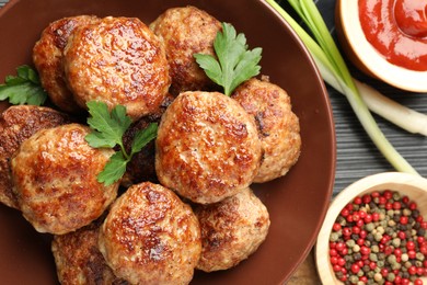 Photo of Delicious patties and spices on black textured table, flat lay