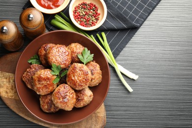 Photo of Delicious patties and spices on black textured table, flat lay. Space for text