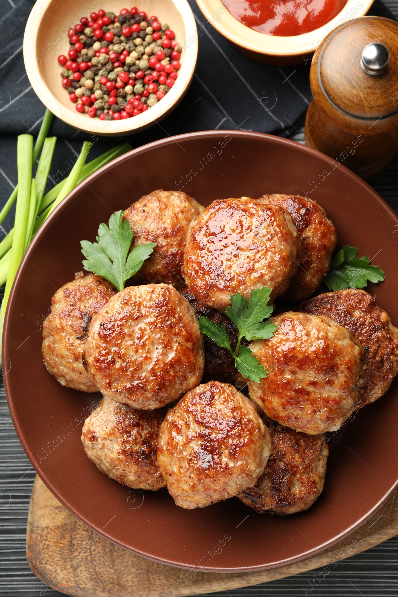 Photo of Delicious patties and spices on black textured table, flat lay