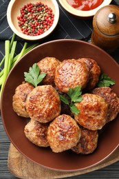 Photo of Delicious patties and spices on black textured table, flat lay