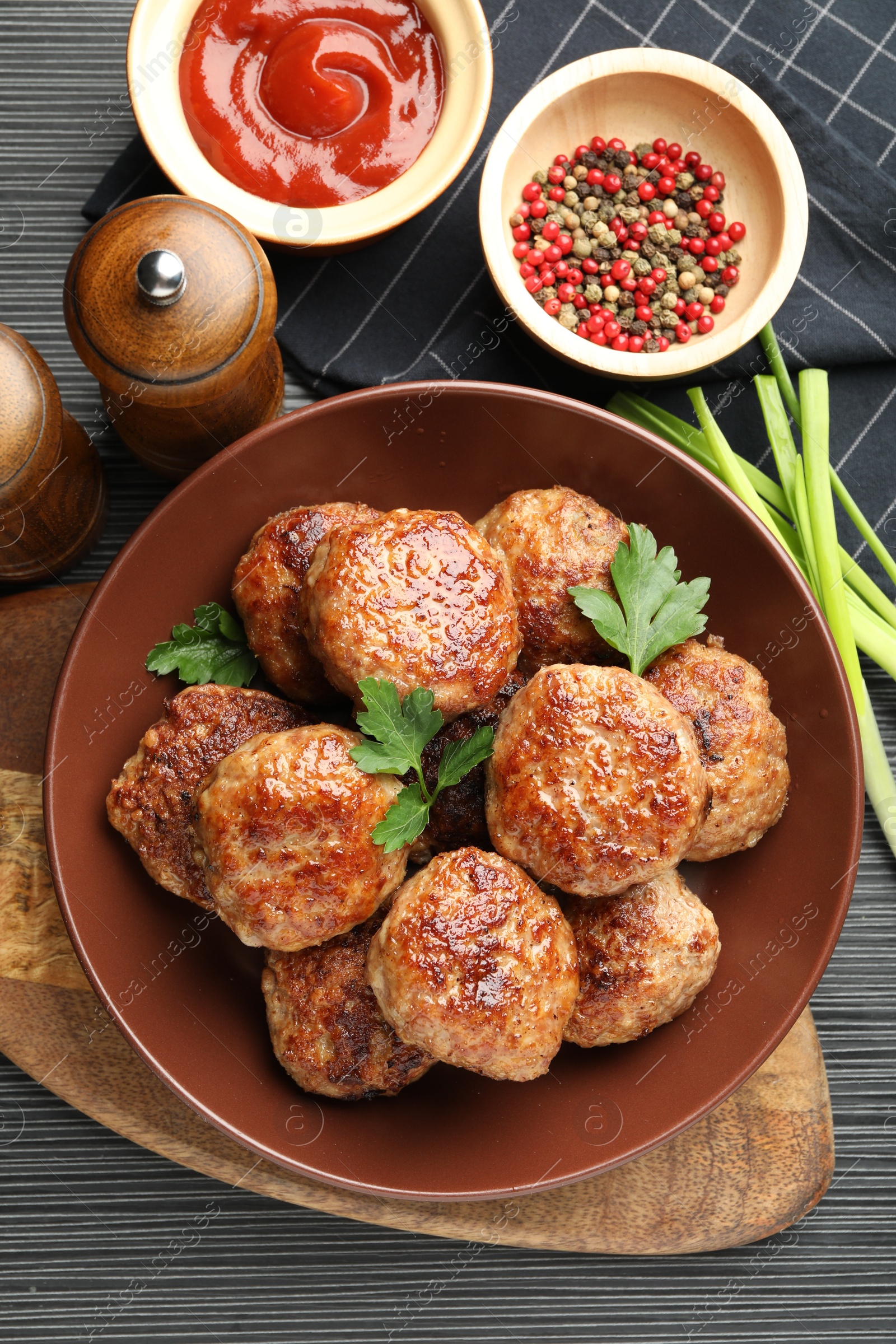 Photo of Delicious patties and spices on black textured table, flat lay