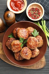 Photo of Delicious patties and spices on black textured table, flat lay