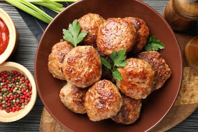 Photo of Delicious patties and spices on black textured table, flat lay