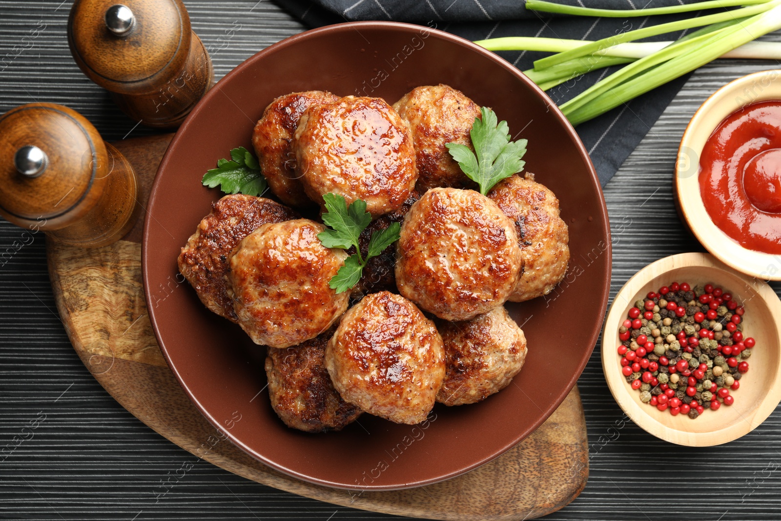 Photo of Delicious patties and spices on black textured table, flat lay