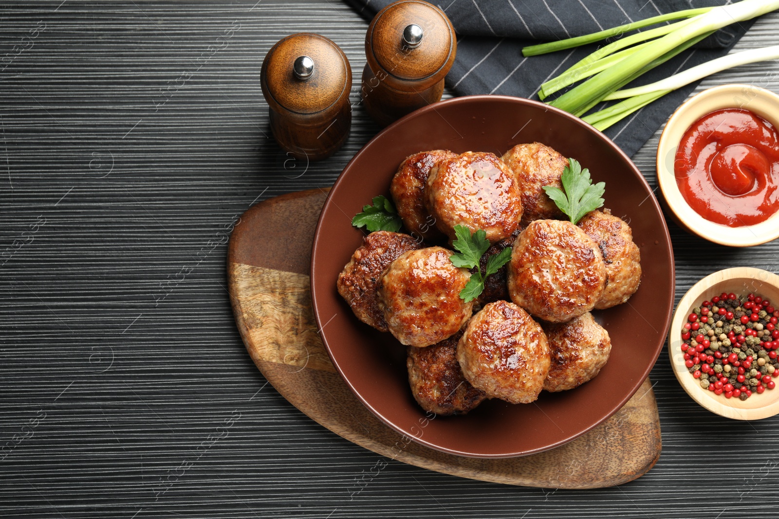 Photo of Delicious patties and spices on black textured table, flat lay. Space for text