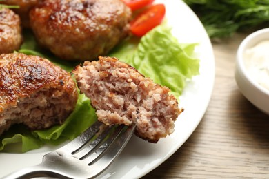 Photo of Eating delicious patty at wooden table, closeup