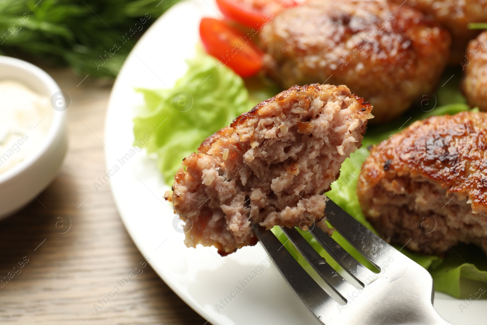 Photo of Eating delicious patty at wooden table, closeup