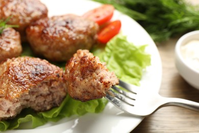 Photo of Eating delicious patty at wooden table, closeup