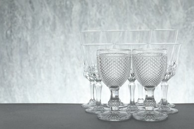 Photo of Many empty clean glasses on grey table. Space for text