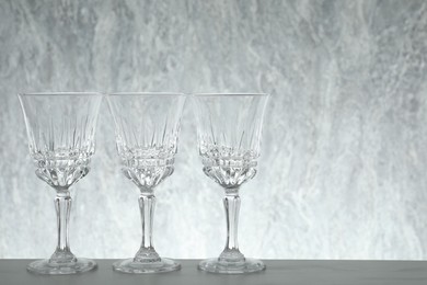 Photo of Three empty clean glasses on grey table. Space for