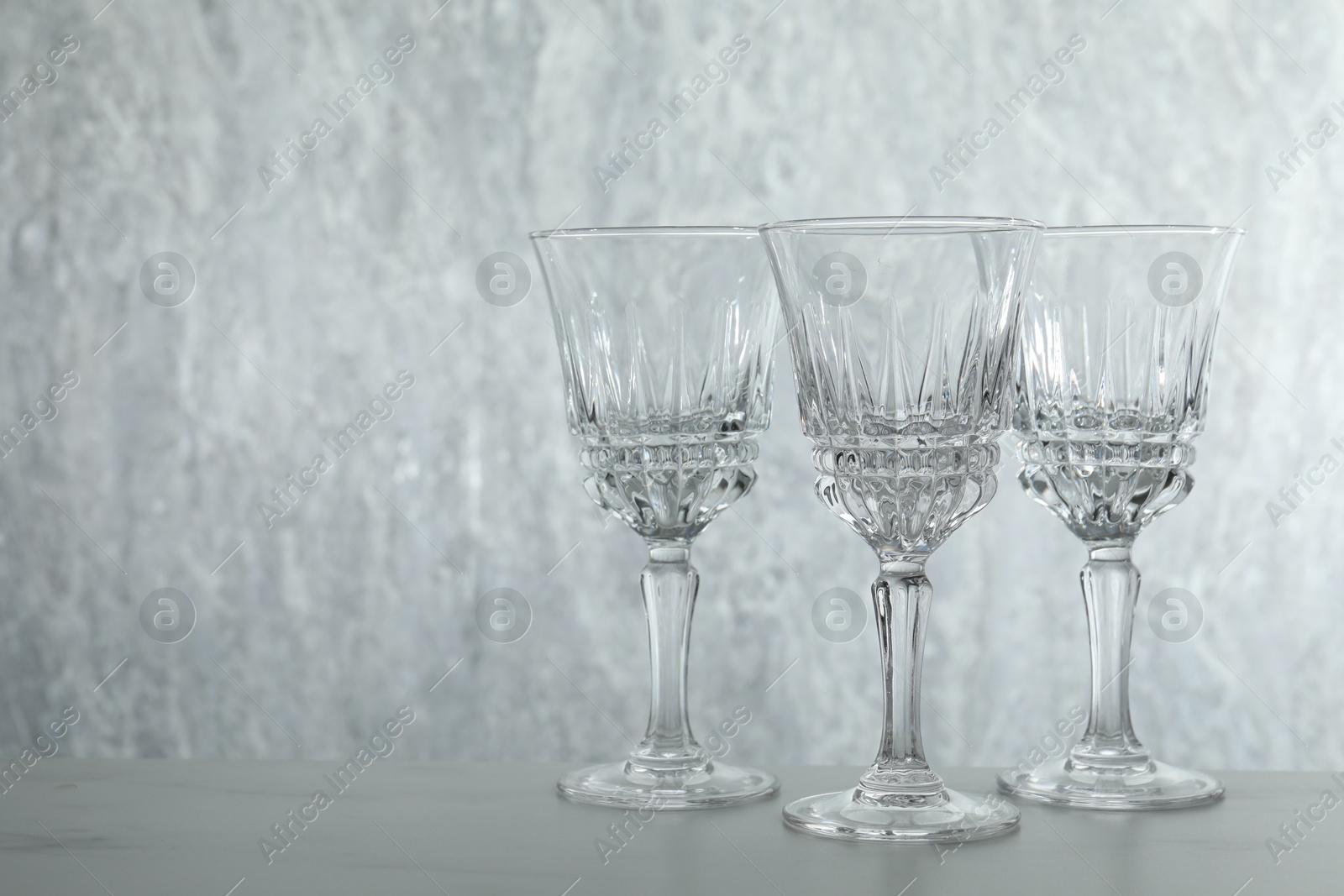 Photo of Three empty clean glasses on grey table. Space for