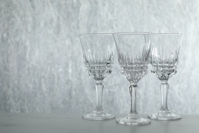 Photo of Three empty clean glasses on grey table. Space for