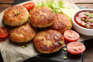 Photo of Delicious patties with green onions, tomatoes and ketchup on table, closeup