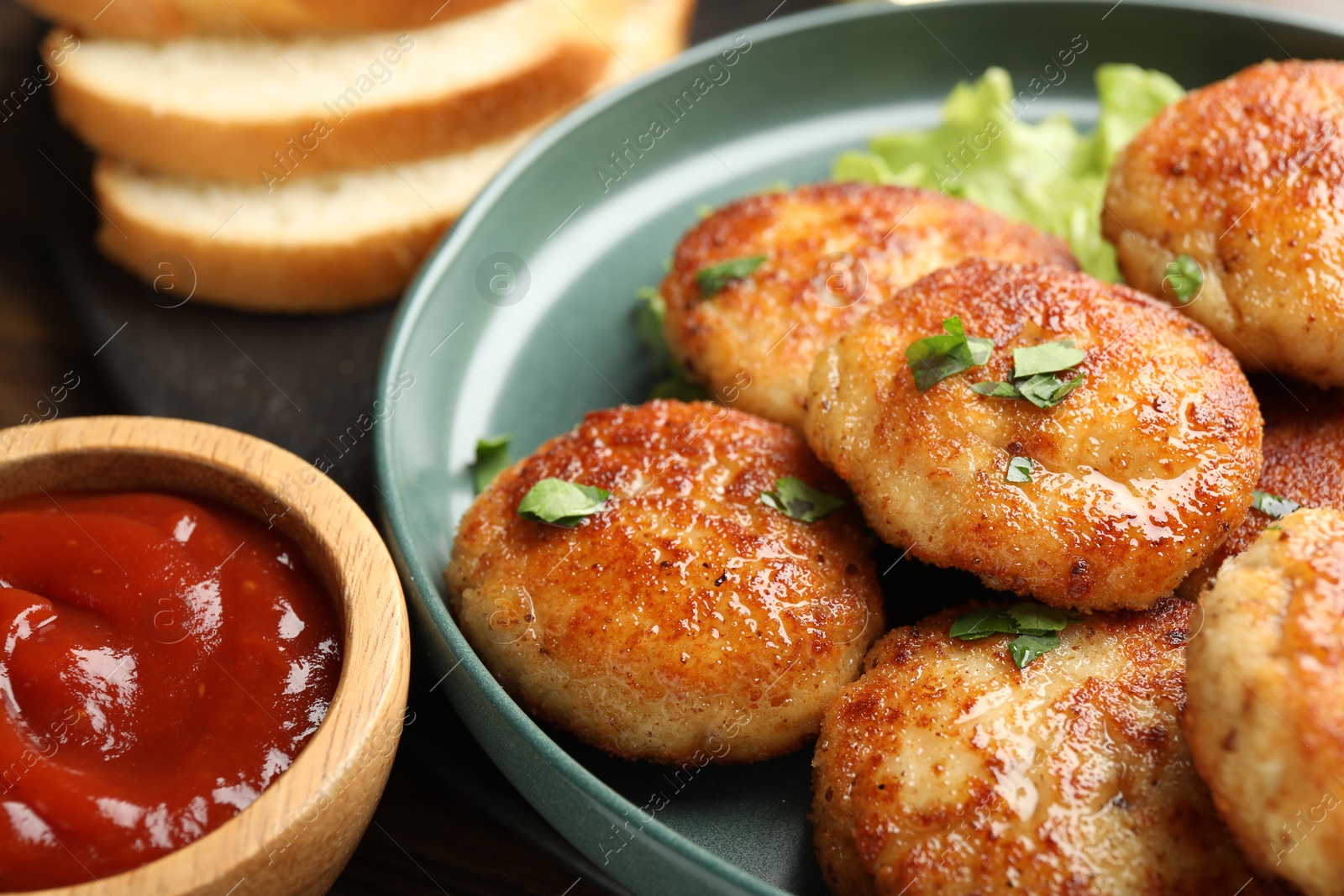 Photo of Delicious patties, parsley and ketchup on table, closeup