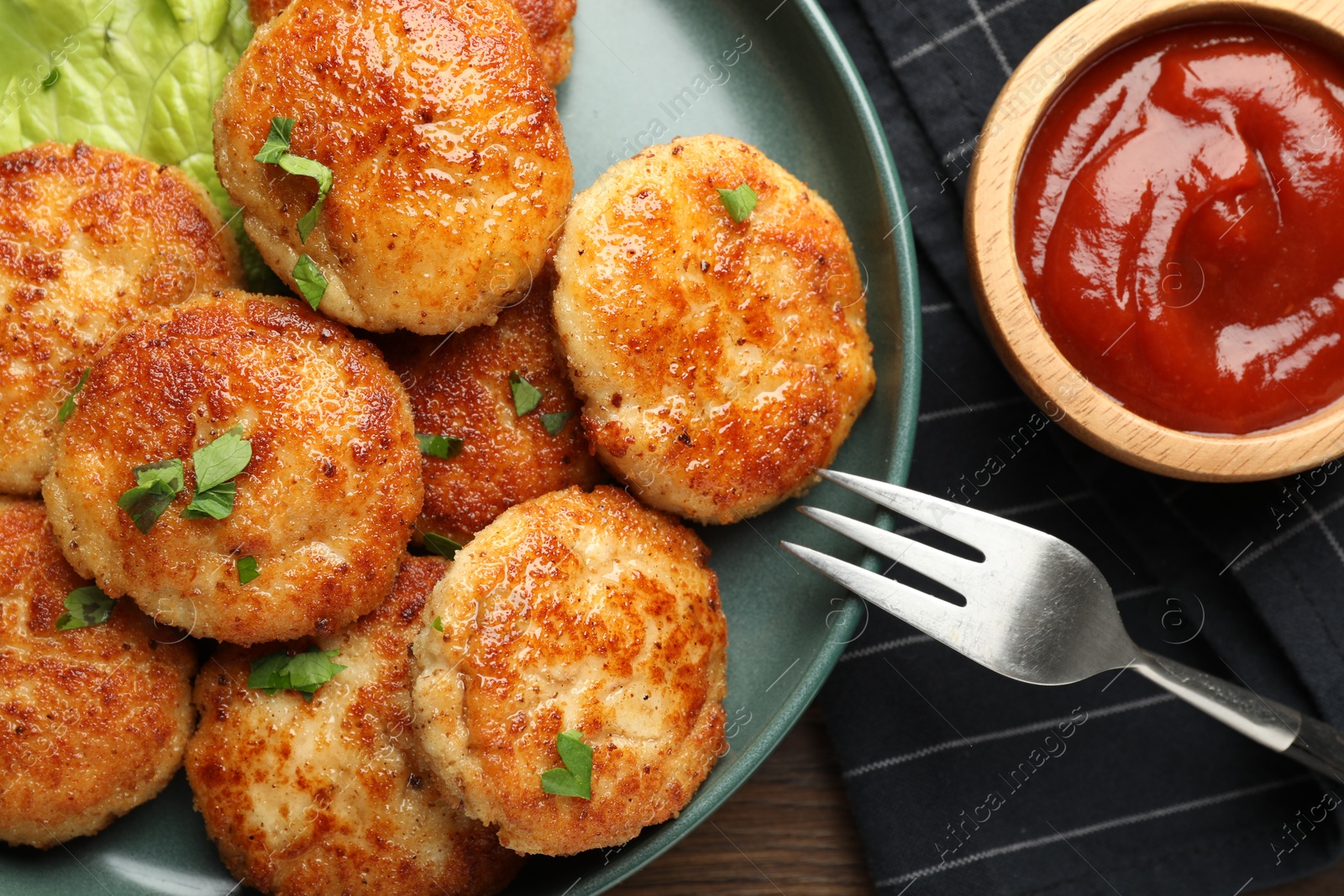 Photo of Delicious patties, parsley, ketchup and fork on table, top view