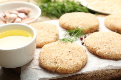 Photo of Many uncooked patties and spices on table, closeup