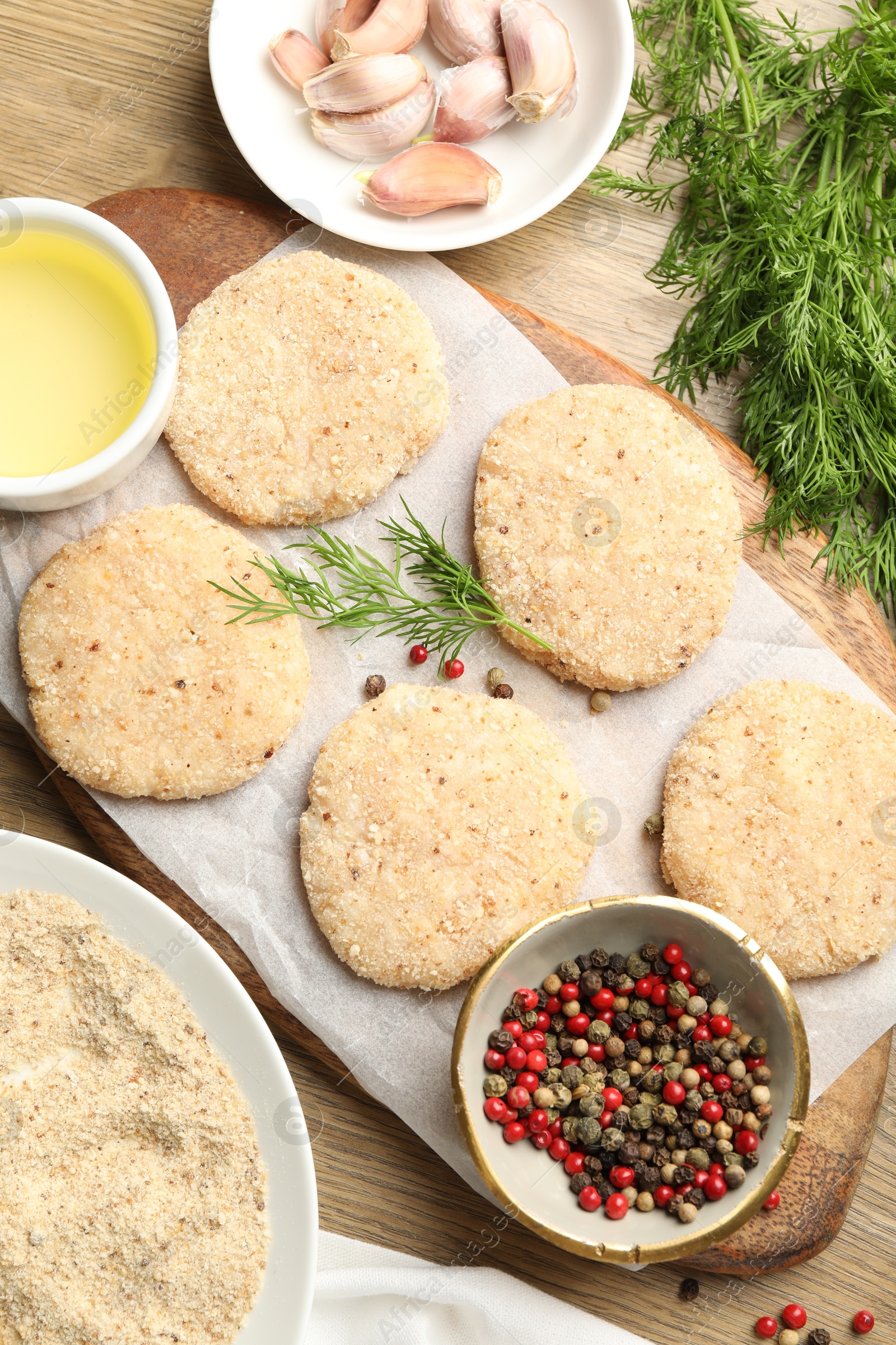 Photo of Many uncooked patties and spices on wooden table, flat lay