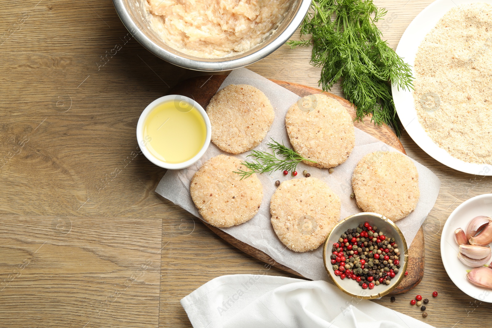 Photo of Many uncooked patties and spices on wooden table, flat lay. Space for text