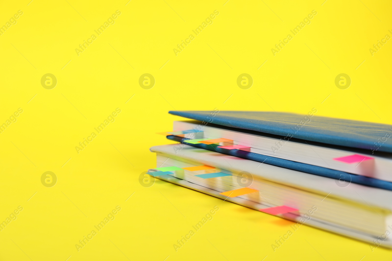 Photo of Books with colorful tabs on yellow background, closeup. Space for text