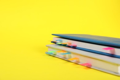 Photo of Books with colorful tabs on yellow background, closeup. Space for text