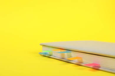 Photo of Book with colorful tabs on yellow background, closeup. Space for text