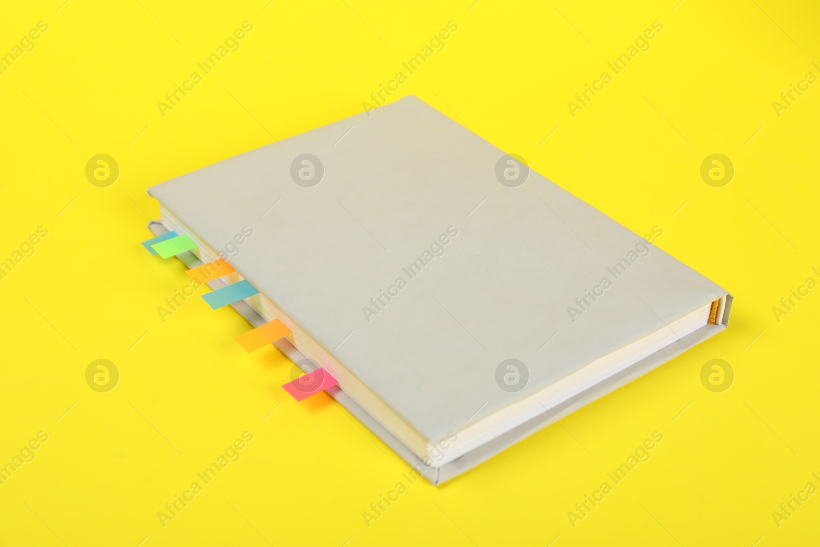 Photo of Book with colorful tabs on yellow background, closeup