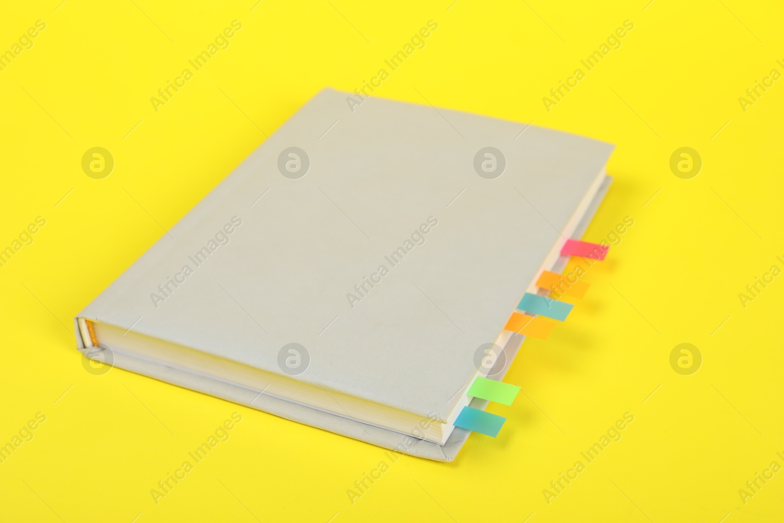 Photo of Book with colorful tabs on yellow background, closeup