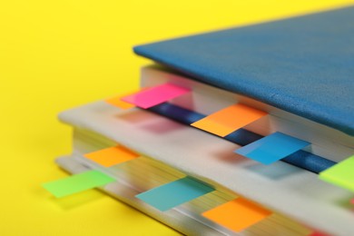 Photo of Books with colorful tabs on yellow background, closeup