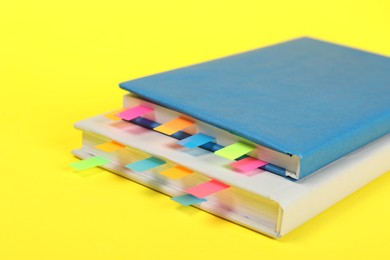 Photo of Books with colorful tabs on yellow background, closeup