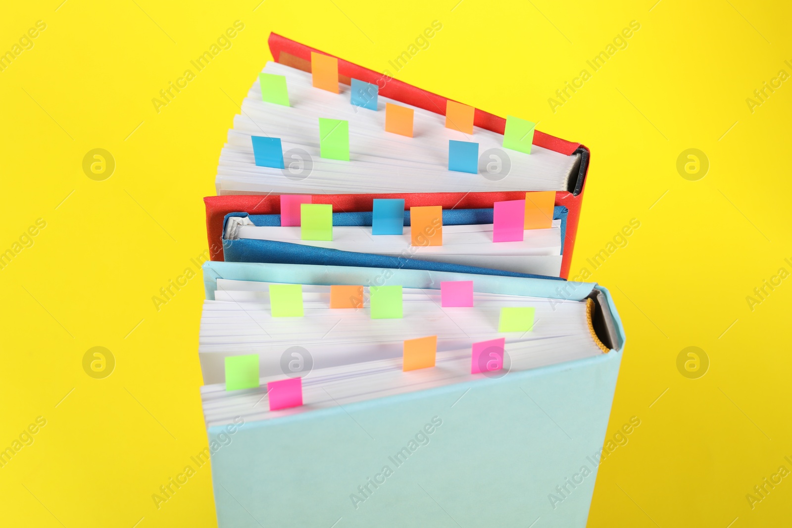 Photo of Books with colorful tabs on yellow background, closeup