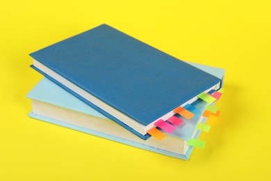 Photo of Books with colorful tabs on yellow background, closeup