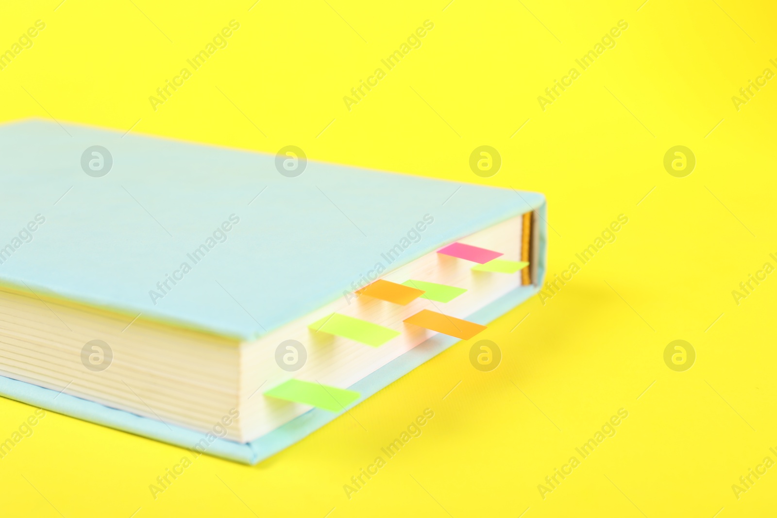 Photo of Book with colorful tabs on yellow background, closeup