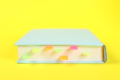 Photo of Book with colorful tabs on yellow background, closeup