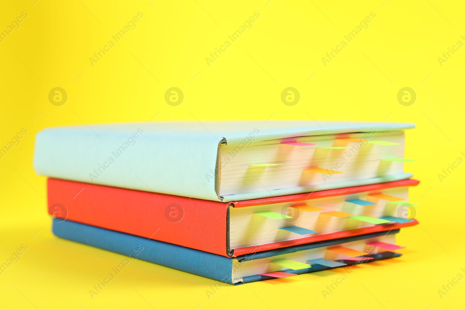 Photo of Books with colorful tabs on yellow background, closeup