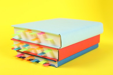 Photo of Books with colorful tabs on yellow background, closeup