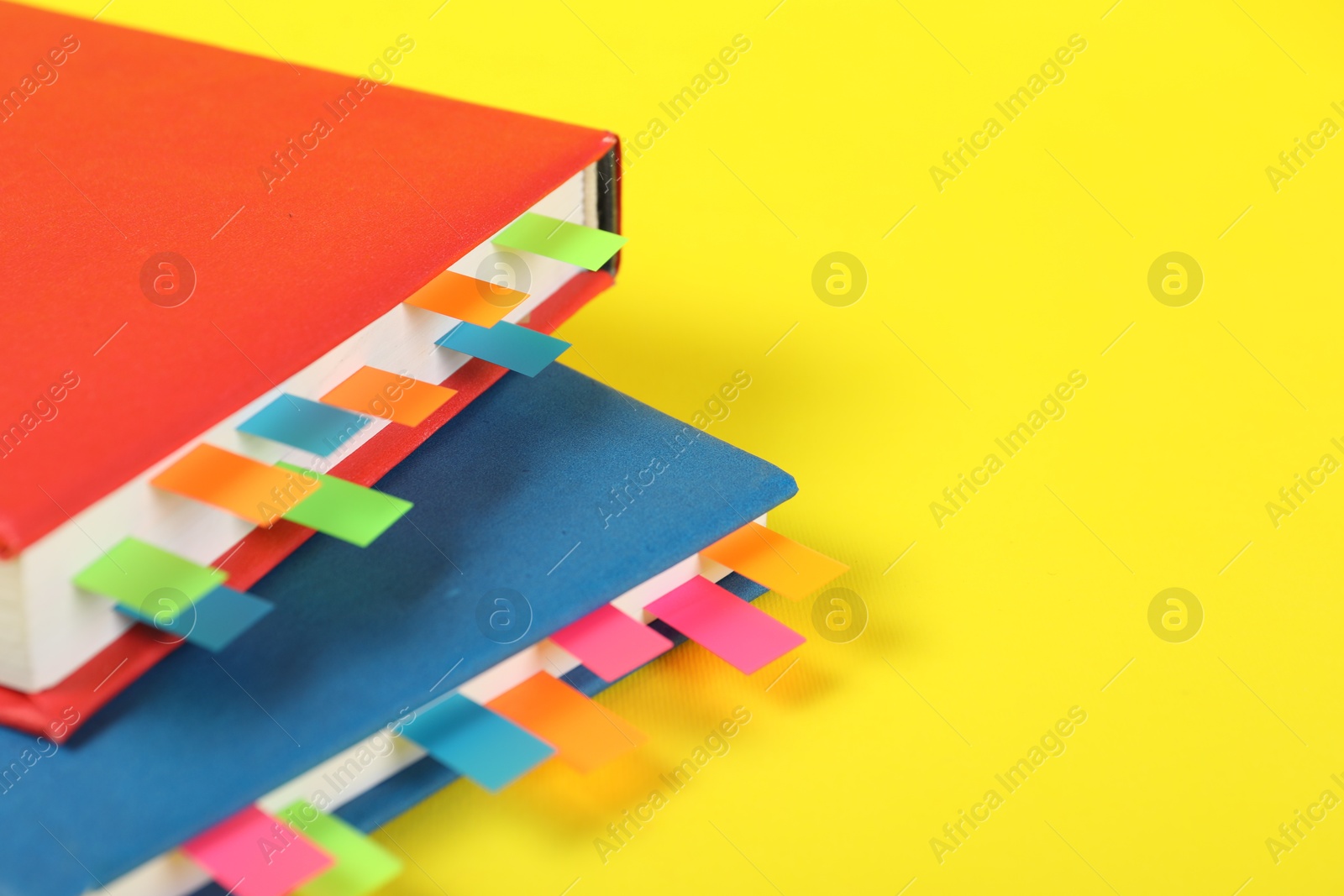 Photo of Books with colorful tabs on yellow background, closeup. Space for text