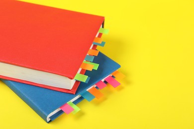 Photo of Books with colorful tabs on yellow background, closeup. Space for text