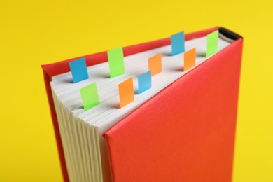 Photo of Book with colorful tabs on yellow background, closeup