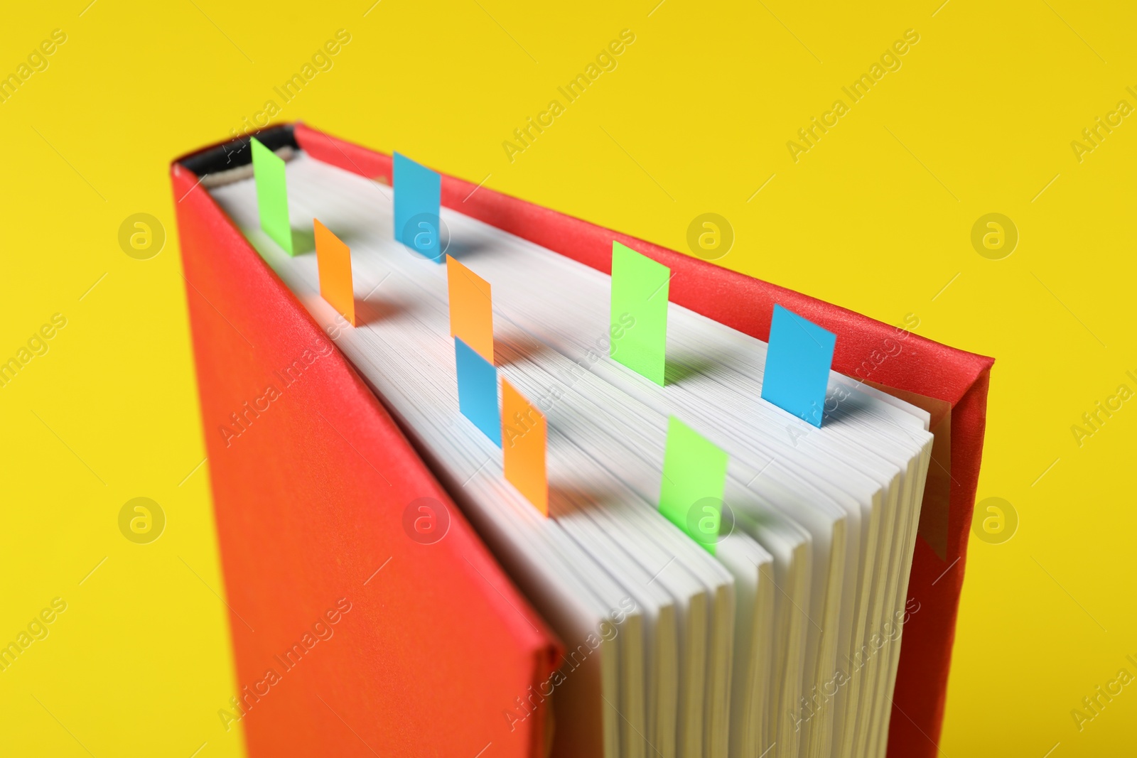 Photo of Book with colorful tabs on yellow background, closeup