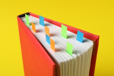 Photo of Book with colorful tabs on yellow background, closeup