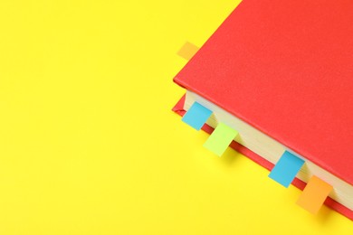 Photo of Book with colorful tabs on yellow background, closeup. Space for text