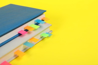 Photo of Books with colorful tabs on yellow background, closeup. Space for text