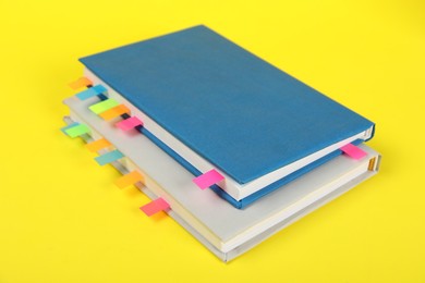 Photo of Books with colorful tabs on yellow background, closeup