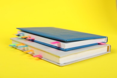 Photo of Books with colorful tabs on yellow background, closeup