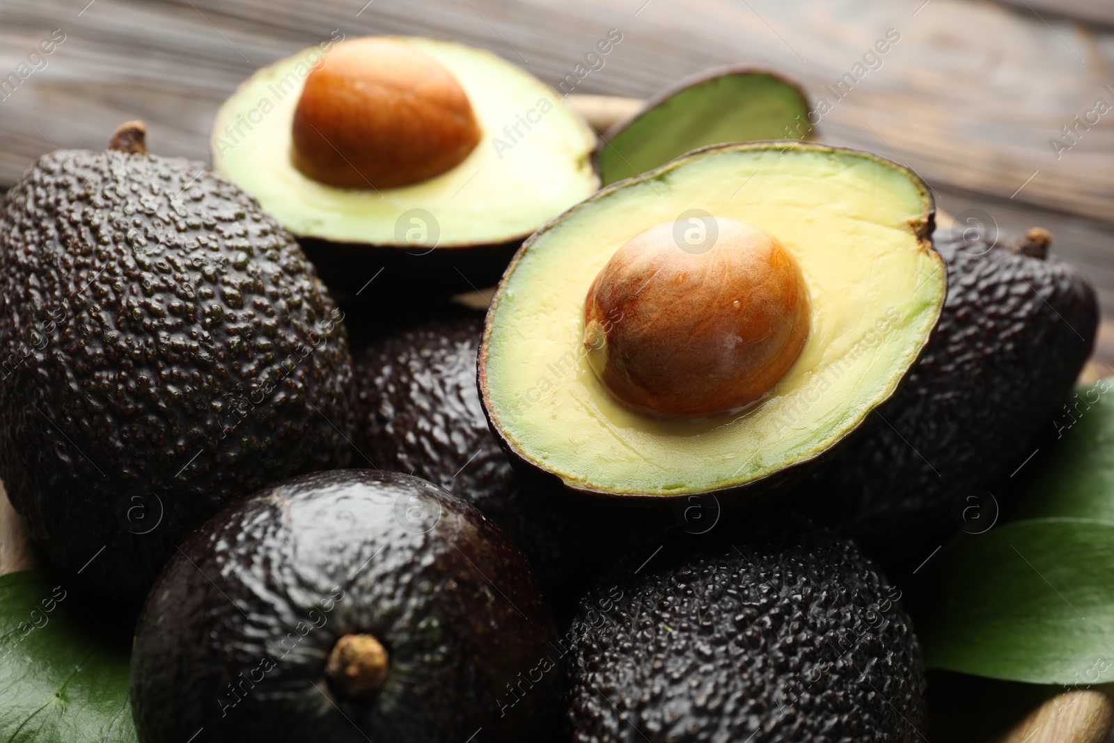 Photo of Whole and cut avocados on table, closeup