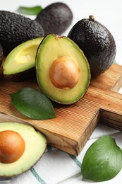 Photo of Whole and cut avocados on white table, closeup