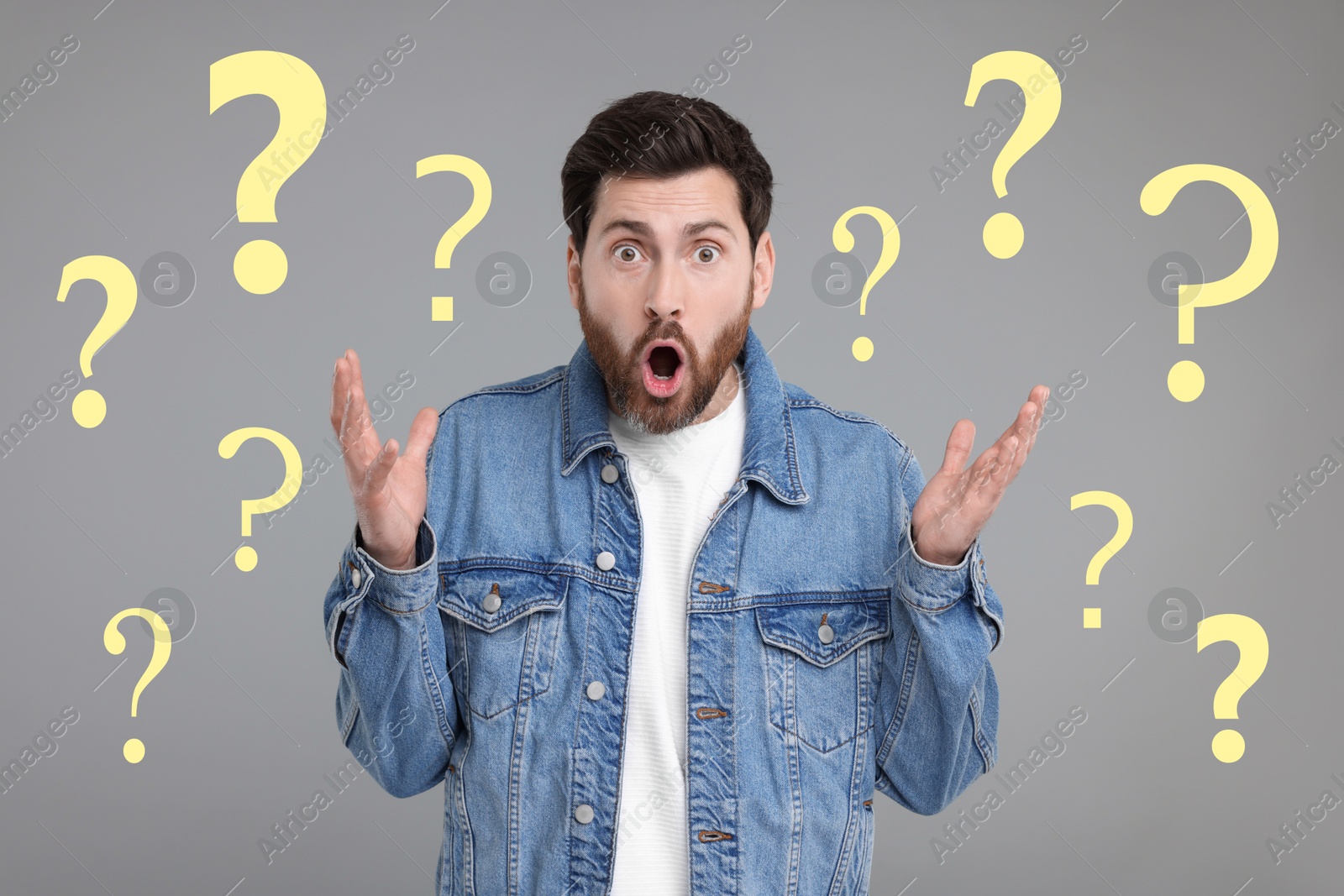 Image of Shocked man surrounded by question marks on grey background