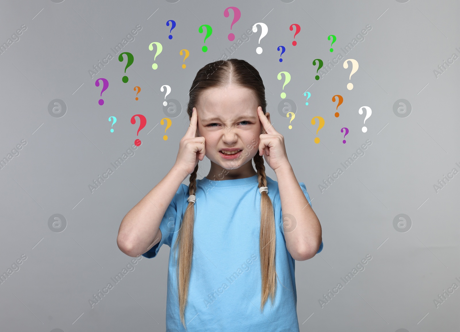 Image of Little girl thinking hard surrounded by question marks on grey background