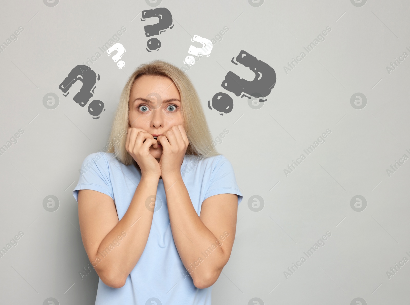 Image of Shocked woman on light grey background. Question marks around her